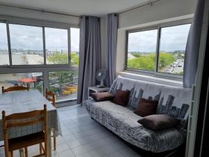 un salon avec un canapé et quelques fenêtres dans l'établissement Bel appartement T2, 50 m de la plage des Minimes, La Rochelle,, à La Rochelle