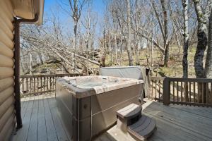 a jacuzzi tub on a wooden deck with trees at Western Wonder in Beech Mountain