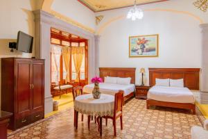 a bedroom with two beds and a table and a tv at HOTEL CASONA MISIONES in Querétaro