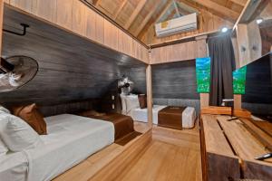 a room with two beds in a room with wooden walls at Central Hotel Bocas del Toro in Valle de Agua