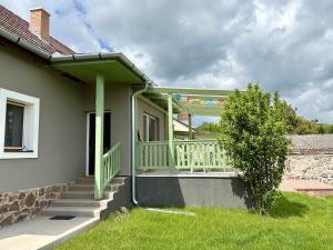 a front porch of a house with a green railing at Három Piszke Vendégház in Mátraszőlős
