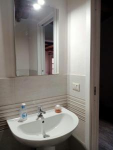 Un lavabo blanco en un baño con espejo. en Casa in campagna, en Monte Argentario