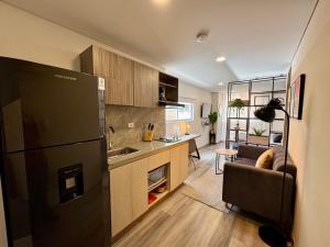 a kitchen with a black refrigerator and a living room at Cozy Loft in 93 park in Bogotá