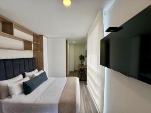 a bedroom with a bed and a flat screen tv at Cozy Loft in 93 park in Bogotá