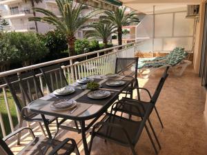 a table and chairs on a balcony with palm trees at Vernisa Apartamento Numero Uno in Playa de Gandia