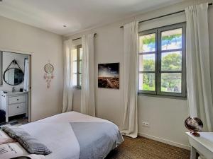 a bedroom with a bed and two windows at Villa du Littoral in Grimaud