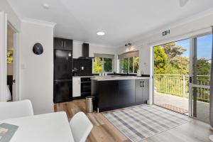 a kitchen with black and white appliances and a balcony at Nana Glads of Paihia in Paihia