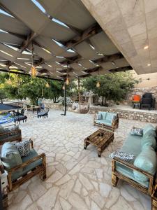 a patio with couches and benches on a stone floor at Oak Farm مزرعة البلوط in Ajloun