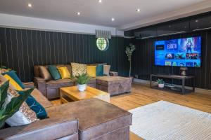 a living room with couches and a flat screen tv at Huge 8 Bed Manor House with Hot Tub, Cinema Room, Games Room in Hailsham