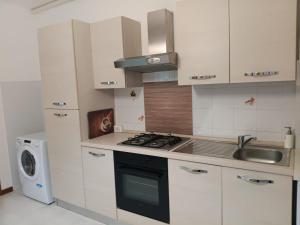 a kitchen with white cabinets and a stove and a sink at Casa Girasole in Bellinzago Lombardo