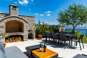 オパティヤにあるVilla K Opatija with a heated pool, sauna, astonishing sea viewのパティオ(暖炉、テーブル、椅子付)