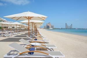 een rij ligstoelen en parasols op een strand bij The First Collection Dubai Jumeirah Village Circle, a Tribute Portfolio Hotel in Dubai