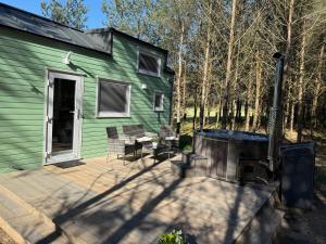 a green house with a patio and a grill at Tiny house in the forest in Szlachta