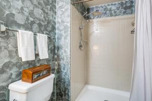 a bathroom with a shower and a toilet with a clock on it at 1 Mi to Boardwalk Convenient North Beach Apt! in North Beach +16 photos