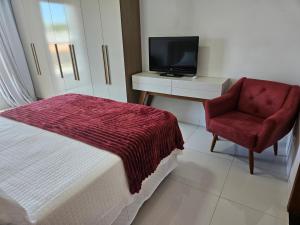 a bedroom with a bed and a chair and a television at Casa Bella com piscina 1504 sul in Santo Antônio