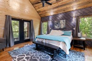 a bedroom with a bed and a wooden wall at Cozy Luxe Cabin Hot Tub Firepit in Broken Bow