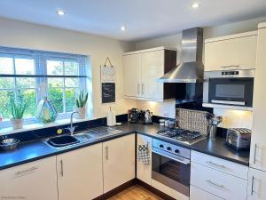 a kitchen with white cabinets and a stove top oven at Paddys Corner in Filey