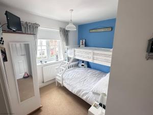 a small bedroom with a bunk bed and blue walls at Paddys Corner in Filey +39 photos