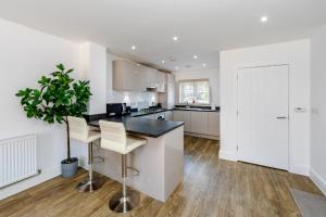a kitchen with white walls and a island with bar stools at My Chester Luxury Home in Colchester +19 photos