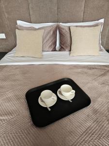 a tray with two cups and saucers on a bed at Luxury Penthouse with Private Jacuzzi & Sea View in Durrës