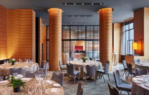 a dining room with tables and chairs and large windows at The Lofton Hotel Minneapolis, Tapestry Collection by Hilton in Minneapolis