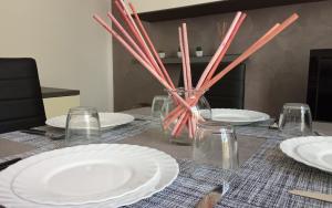 une table avec des assiettes blanches et un vase avec des bâtons dans l'établissement Apartment, Marina di Ravenna, à Marina di Ravenna