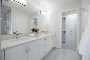 ein weißes Badezimmer mit Waschbecken und Spiegel in der Unterkunft Home Theater with AC, Dual Master Suites, BBQ in Calgary + 37 Fotos