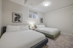 zwei Betten in einem Zimmer mit weißen Wänden in der Unterkunft Home Theater with AC, Dual Master Suites, BBQ in Calgary