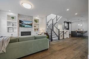 ein Wohnzimmer mit einer grünen Couch und einer Treppe in der Unterkunft Home Theater with AC, Dual Master Suites, BBQ in Calgary