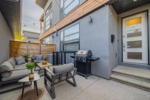 eine Terrasse mit einer Couch und einem Grill neben einem Gebäude in der Unterkunft Home Theater with AC, Dual Master Suites, BBQ in Calgary