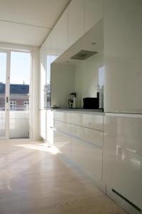 kuchnia z białymi szafkami i dużym oknem w obiekcie Thorshavnsgade Apartment w Kopenhadze