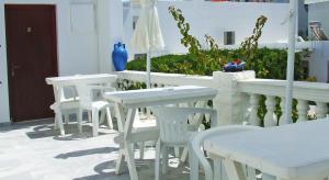 um grupo de mesas e cadeiras brancas num pátio em Hotel Eleftheria em Parikia