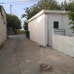 an empty road next to a white building at Ikarian Family Cottage, Ikaria Droutsoulas in Akamatra +5 photos