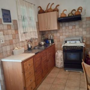 a kitchen with wooden cabinets and a stove top oven at Ikarian Family Cottage, Ikaria Droutsoulas in Akamatra