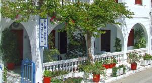 a white building with trees and potted plants at Hotel Eleftheria in Parikia