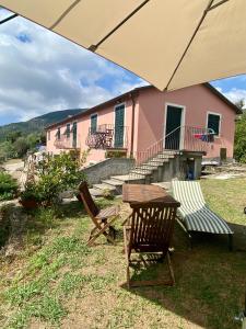 Una mesa, sillas y una sombrilla frente a un edificio rosa. en Villa Giovanna Apt. B, en Sestri Levante