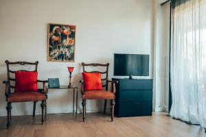 un salon avec deux chaises et une télévision dans l'établissement Varkiza Luxury Escape, à Vari