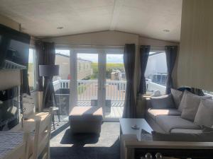 a living room with a couch and a balcony at Gracie's Retreat in Skipsea