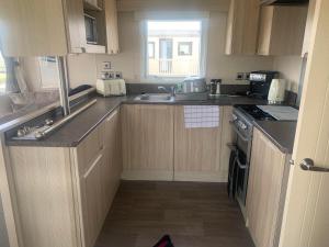 a small kitchen with wooden cabinets and a sink at Gracie's Retreat in Skipsea