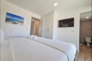 Un dormitorio blanco con una cama blanca y un baño. en Exclusive NEW luxury townhouse with pool in PALM BEACH, en Palm-Eagle Beach 28 fotos más