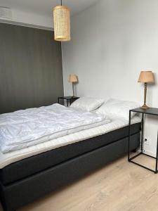 a bed in a room with two tables and two lamps at Helgatunlia - Leilighet 2 in Vossevangen
