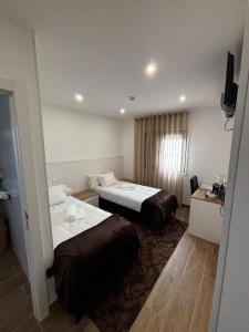 ein Hotelzimmer mit zwei Betten und einem Fernseher in der Unterkunft Solar de São Pedro in Monção