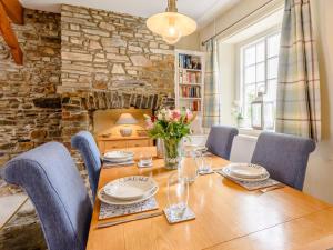 a dining room with a table and chairs and a stone wall at 2 bed in Appledore TRQCT in Appledore