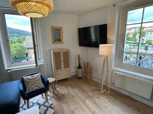 a living room with a tv and two windows at Gîte Cosy - 90m2 - T4 - Climatisé - Tout équipé in Retournac