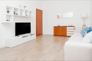 een woonkamer met een witte bank en een televisie bij La Maison Calasetta in Calasetta