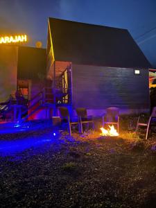 a fire pit with chairs and a building at night at Hideaway Kazbegi in Stepantsminda +31 photos