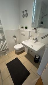 a bathroom with a white sink and a toilet at DUHA HOMES - Stylisches Apartment, Stellplatz, Küche, Self Check-in in Ingolstadt