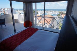 Hôtel Le Nautic في أركاشون: غرفة نوم مع سرير وإطلالة على ميناء