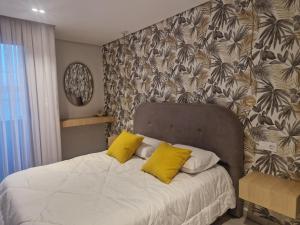a bedroom with a bed with two yellow pillows at Duplex trouville à 2 pas de la plage in Aïn El Turk