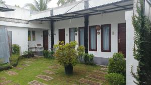 a white house with a tree in the yard at Beruk Angis Guest House & Kost in Palangkaraya +2 photos